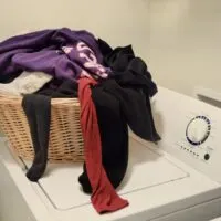 A laundry basket filled with clothes on top of a washing machine with the words 
