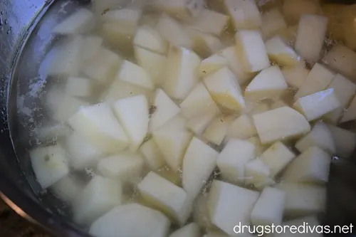 Diced potatoes in a silver bowl filled with water.