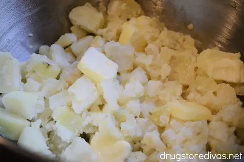 Boiled potato chunks and butter in a silver bowl.
