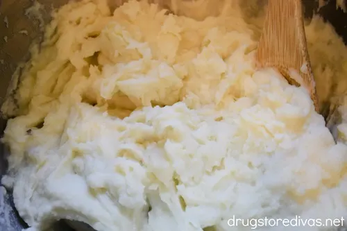 Mashed potatoes in a bowl with a bamboo spoon.