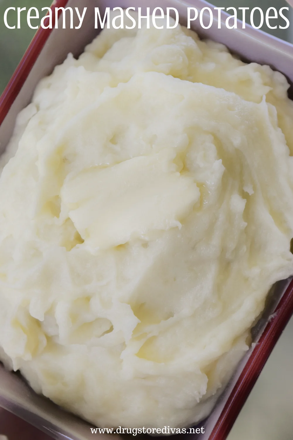 Mashed potatoes with butter on top in a maroon tray and the words 