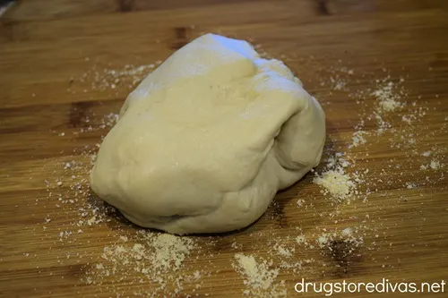 A pizza dough ball on top of cornmeal on a pizza peel.