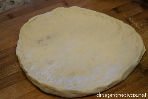 A round, raw, pizza crust on a pizza peel.