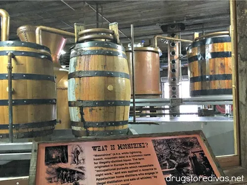 Whiskey barrels behind glass with a sign in front that teaches about moonshine at the Ole Smoky Moonshine distillery in Gatlinburg, TN.
