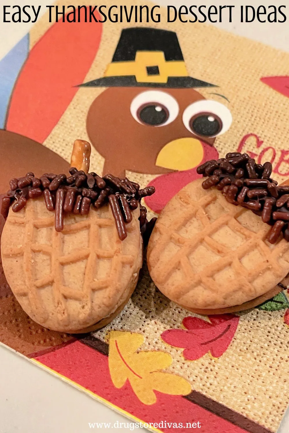 Two acorn cookies on a napkin with a cartoon Thanksgiving turkey on it with the words 