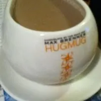 A cup of coffee on a coaster with the words 