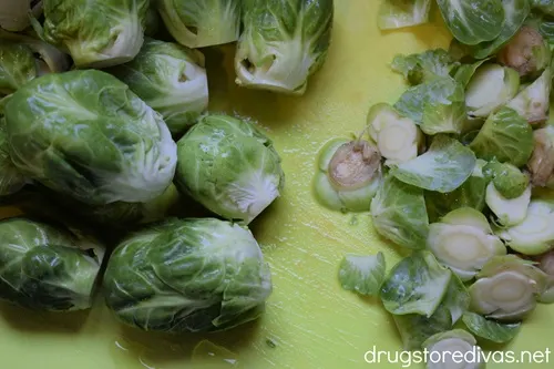 Brussels sprouts with their stems cut off on a green cutting board.
