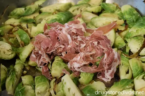Sliced prosciutto on top of Brussels sprouts.