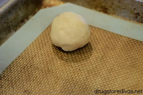 A cookie dough ball on a silicone baking mat.