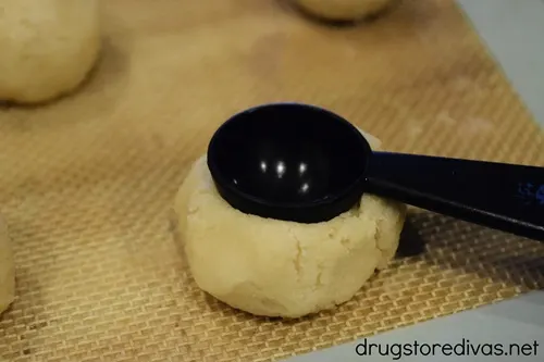 A measuring spoon on top of a cookie dough ball.
