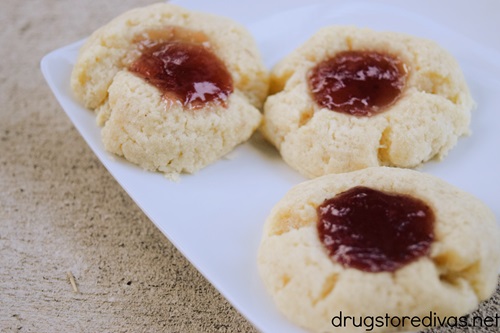Three strawberry thumbprint cookies on a white plate.