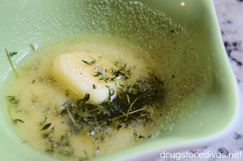 Melted butter, thyme, and salt in a green bowl.