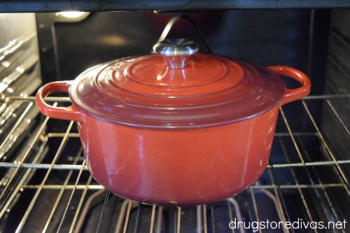 A red Dutch oven with the lid on in the oven.