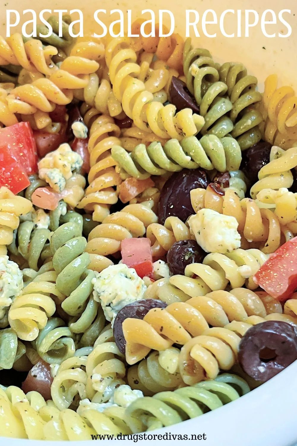 Tri colored pasta with blue cheese, olives, and tomatoes in a white bowl with the words 