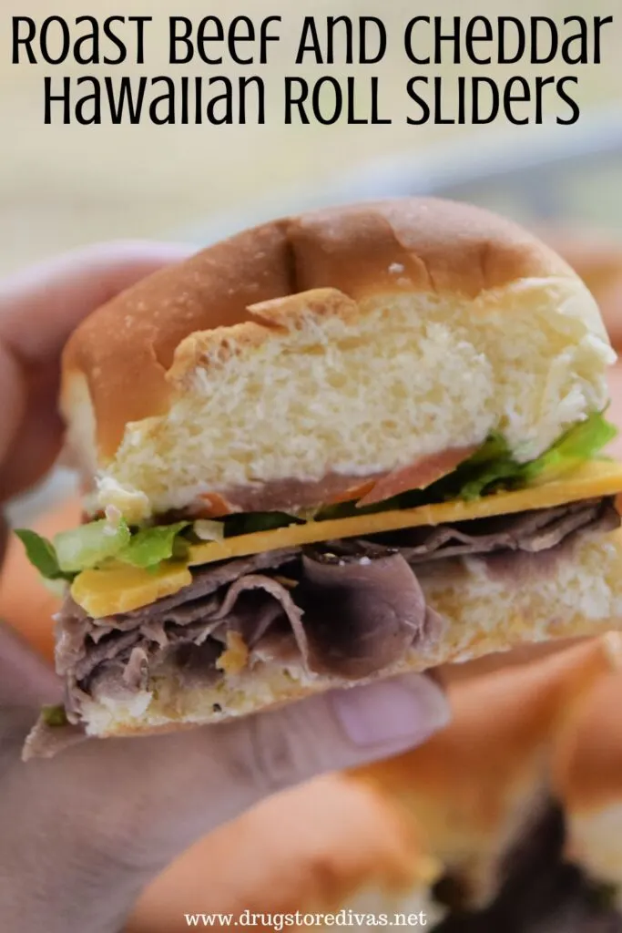 A hand holding a roast beef slider with the words "Roast Beef And Cheese Hawaiian Roll Sliders" digitally written on top.