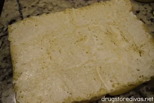 Mayonnaise spread across a Hawaiian roll slicer half.
