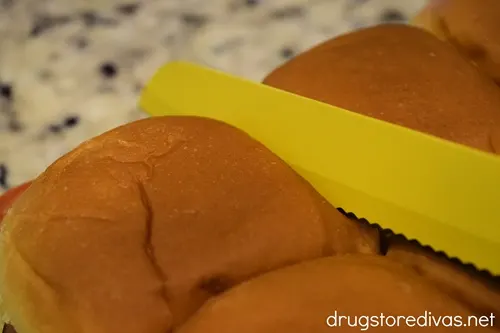 A yellow knife cutting Hawaiian rolls.