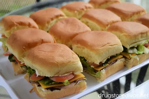 Roast beef and cheddar Hawaiian roll sliders on a white serving tray.