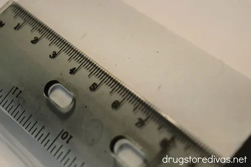 A ruler measuring a toilet paper roll tube.