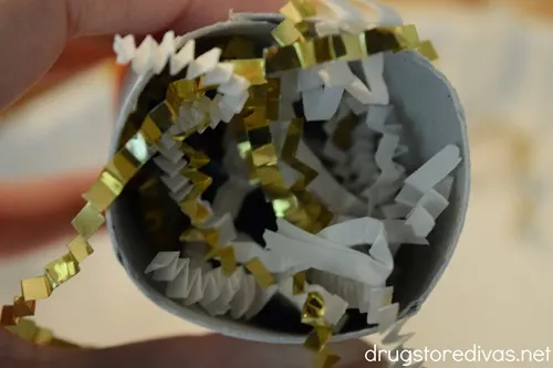White and gold paper shred in a cardboard tube.