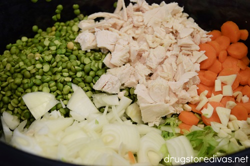 Diced chicken, split peas, sliced carrots, sliced onions, and garlic in a slow cooker.