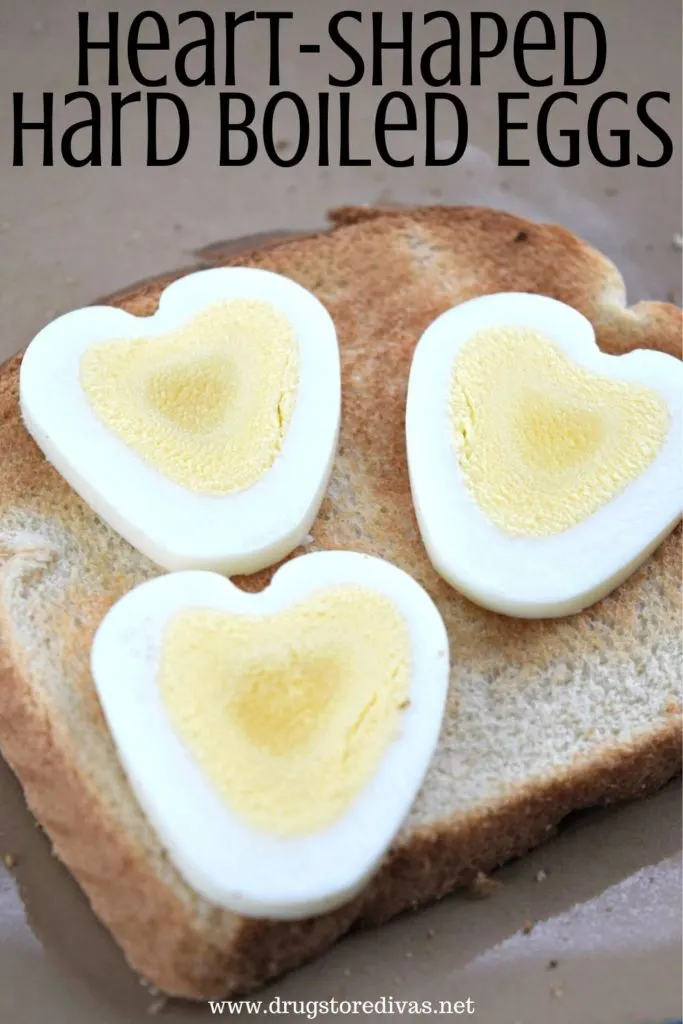 Three heart-shaped hard boiled egg pieces on a piece of bread with the words "Heart-Shaped Hard Boiled Eggs" digitally written on top.