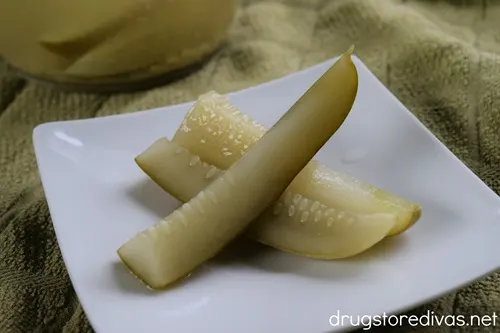 Three pickle spears on a white plate.