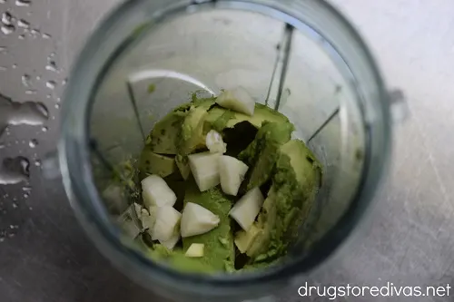 Avocado slices and garlic chunks in a blender cup.