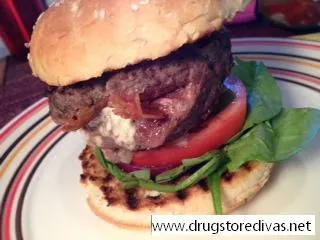 A burger with tomato and spinach on a plate.
