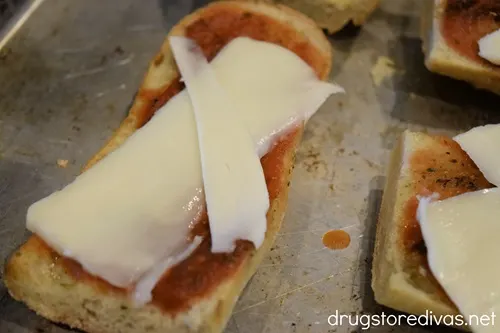Uncooked French bread pizza on a cookie sheet.