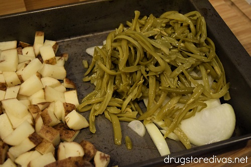 Diced potatoes, sliced onion, and green beans in a pan.