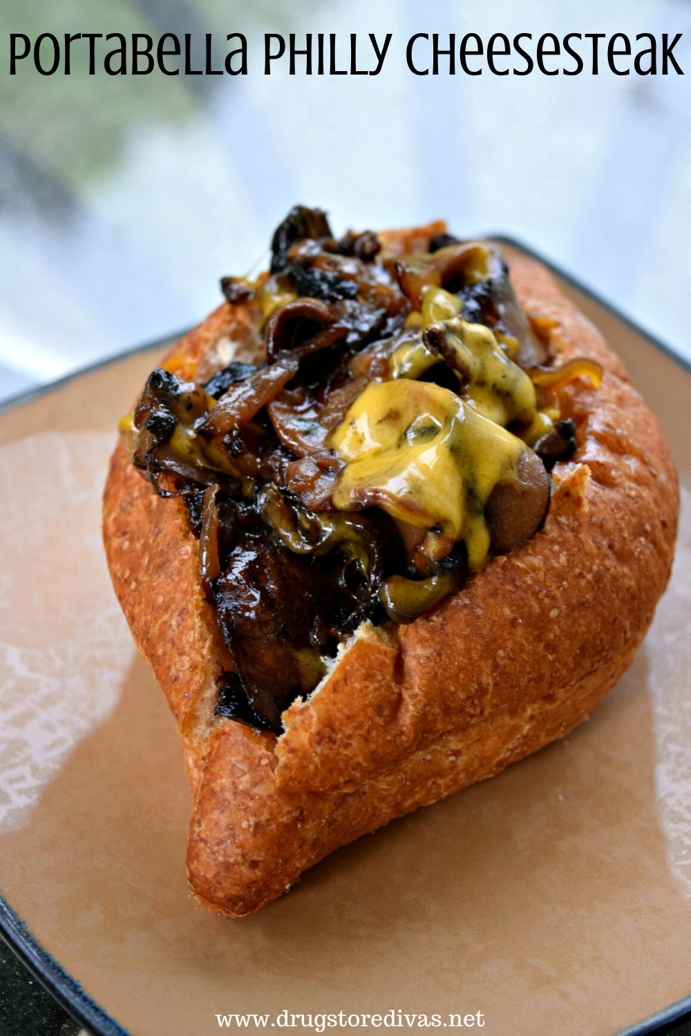 A cheesesteak made with mushrooms in a roll with the words "Portabella Philly Cheesesteak" digitally written on top.