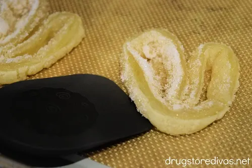 Elephant ear cookies being flipped with a spatula.