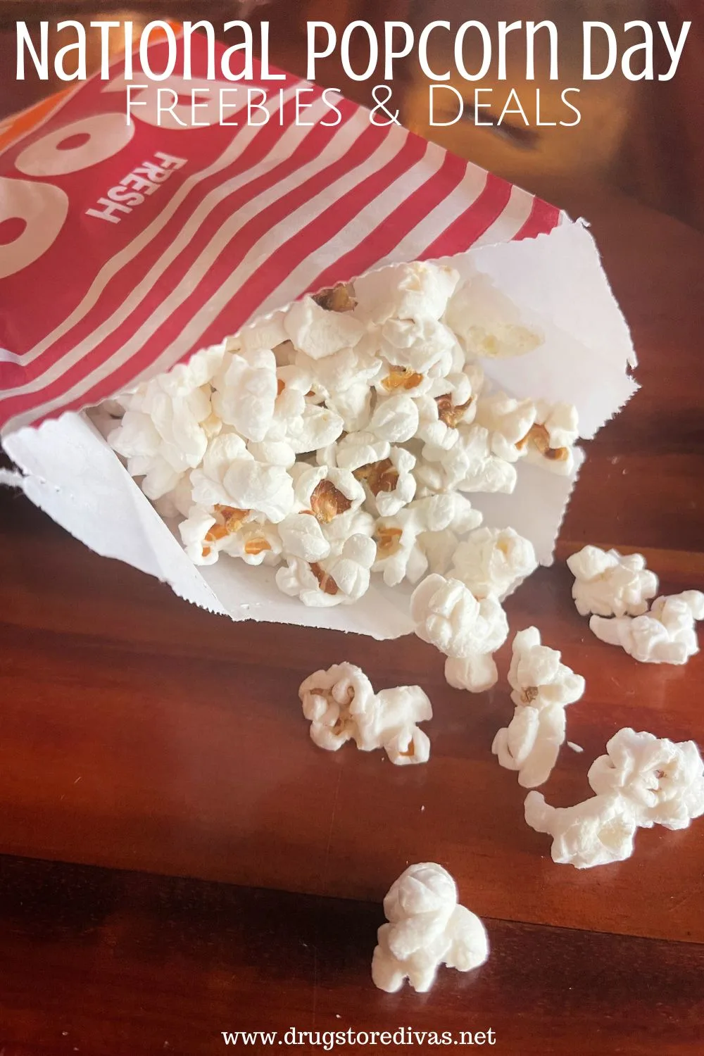 A red and white striped bag with popcorn coming out of it onto a table with the words 