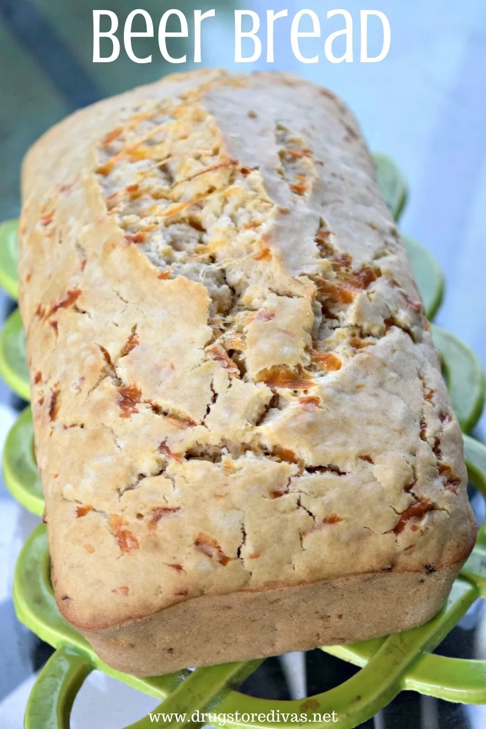 A loaf of beer bread on a green trivet.