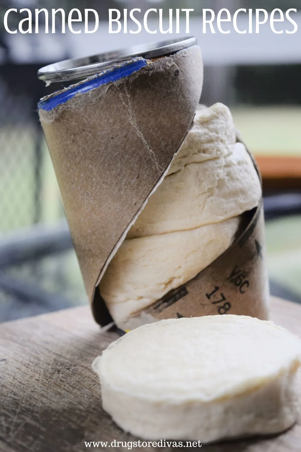 An opened can of refrigerated biscuits with one out on a table and the words 