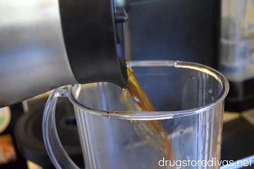 A coffee pot pouring coffee into a plastic pitcher.