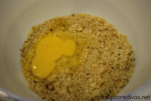 Lemon juice, parmesan cheese, and breadcrumbs with an egg in a bowl.