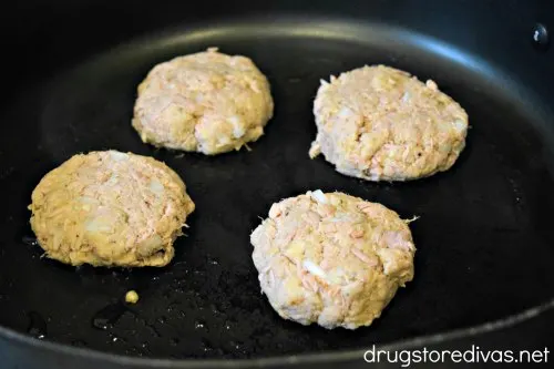 Four uncooked tuna cakes in a skillet.