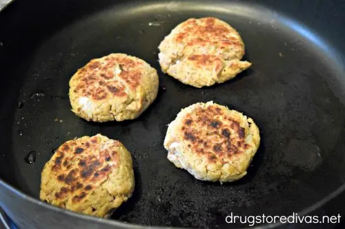 Four cooked tuna cakes in a skillet.