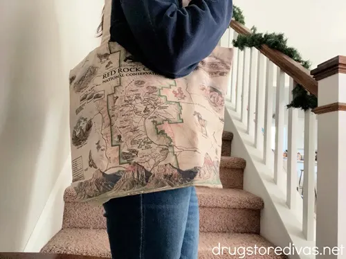 A woman on a staircase carrying a tote bag with a map of Red Rock Canyon on it.
