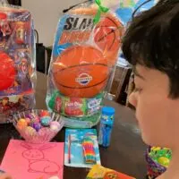 A teen boy in front of two Easter baskets, plus candy, eggs, and a note, with the words 