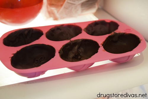 An Easter egg mold filled with chocolate in a fridge.