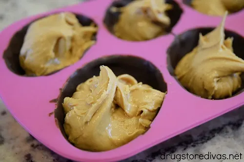Peanut butter in chocolate-filled cavities of a pink egg mold.