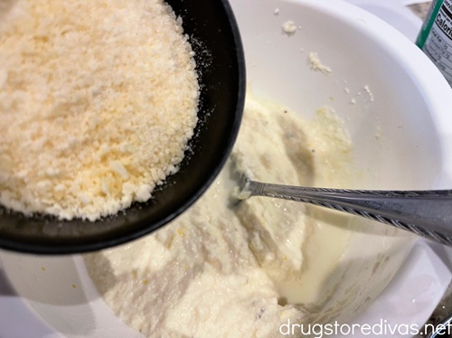 A measuring cup with grated parmesan cheese in it above a bowl with ricotta cheese in it.