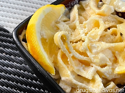 A bowl of lemon ricotta pasta with a lemon wedge in the bowl.