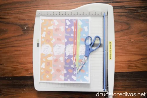 A printable, glow sticks, and scissors on top of a paper trimmer.