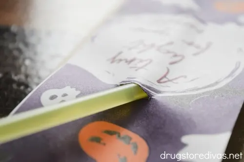 A glow stick going into a slit in a Halloween themed piece of paper.