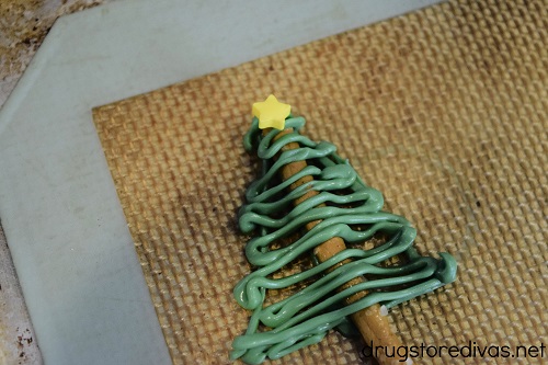 A Chocolate Christmas Tree Pretzel Stick, with a star-shaped sprinkle on top, on a silicone baking mat.
