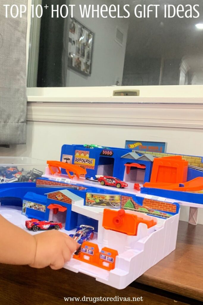 Hot Wheels gas station lay set on a table with the hand and arm of a child holding a car.